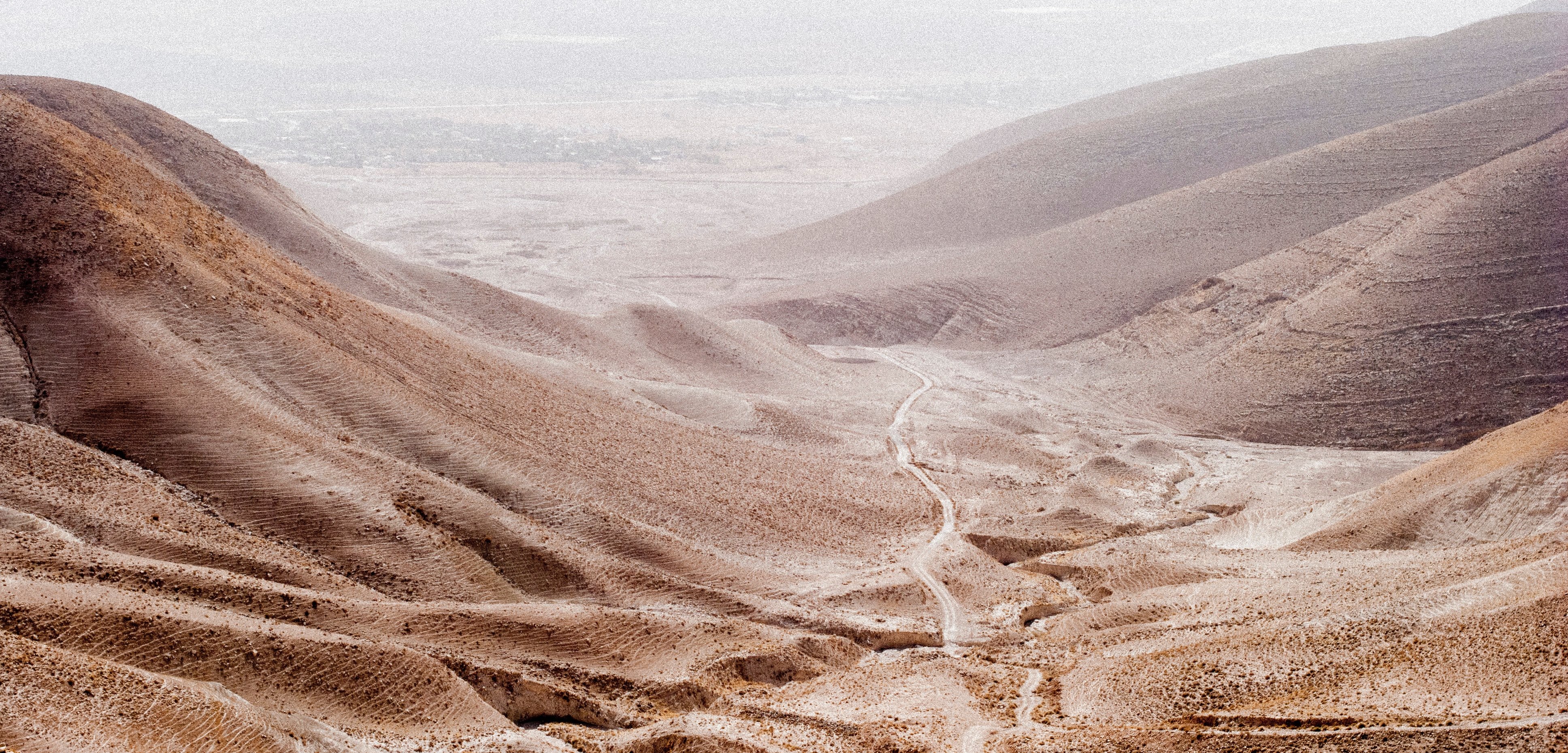 Wüstenlandschaft mit Bergen links und rechts und einem Pfad in der Mitte | © Carolina Stigson on unsplash 
